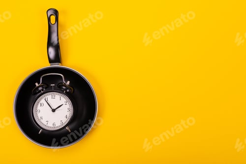 Preview: top view of alarm Clock in pan isolated on yellow background
