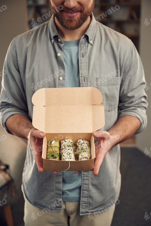 Preview: Man in casual clothes is holding sushi that is in the paper eco box