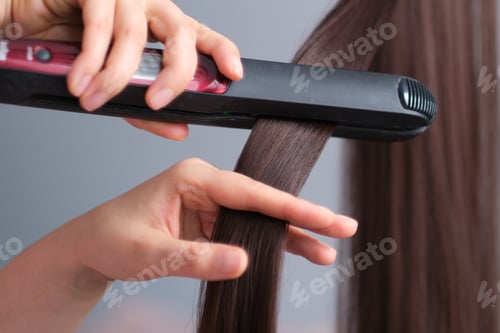 Preview: Woman straight hair using hair straightener. Hair ironing and hairstyle concept