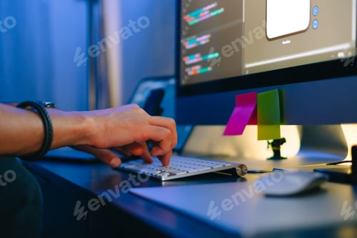 Preview: Mobile developer writes program code on a computer, typing on keyboard
