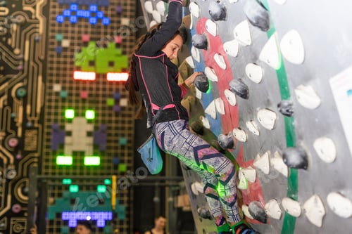 Preview: bouldering, little girl climbing up the wall and climber multicolored grips. Leisure activity