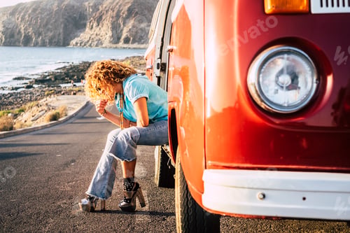 Preview: Trendy woman in travel activity sit down outside a red old vintage van parked on the road
