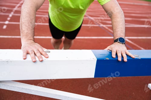 Preview: Athlete doing push-ups on hurdle on running track