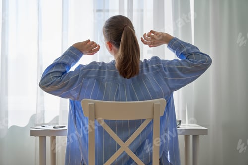 Preview: Unrecognizable woman stretching after long-hours working from home. Remote work difficulties
