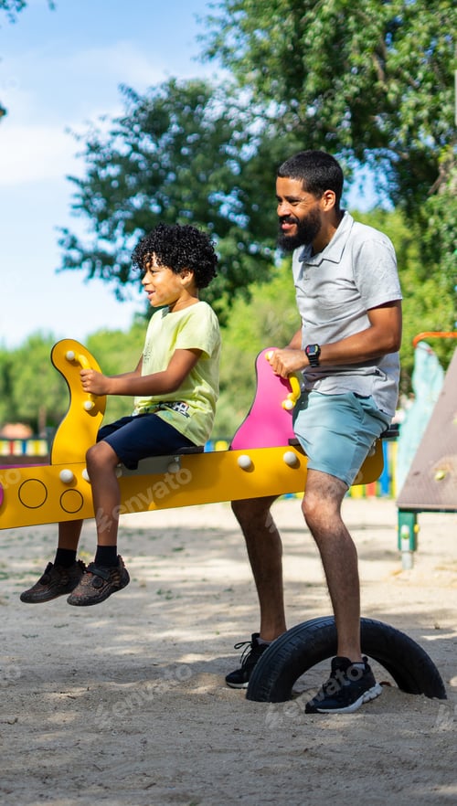 Preview: Latino father and son playing together on a playground swing