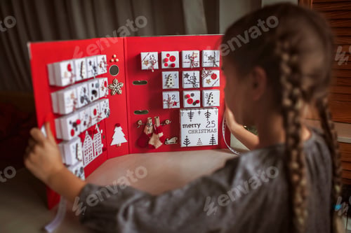 Preview: Pretty girl holds original advent calendar made of jewelry boxes and binder, Christmas diy craft