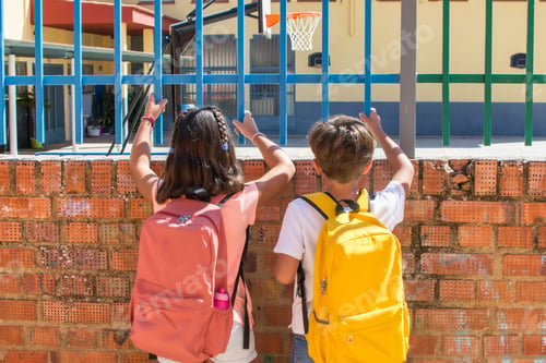 Preview: Children with backpacks looking through school fence
