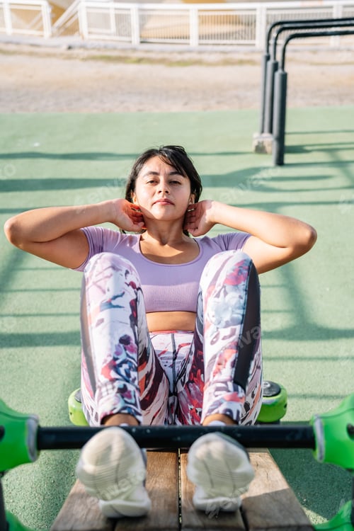 Preview: Determined ethnic woman doing crunches on bench on sandy beach