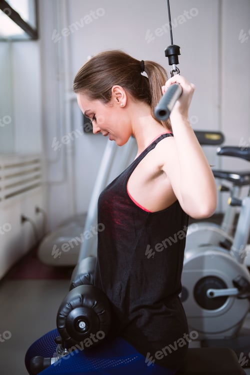 Preview: Young woman doing exercises on a machine at the gym