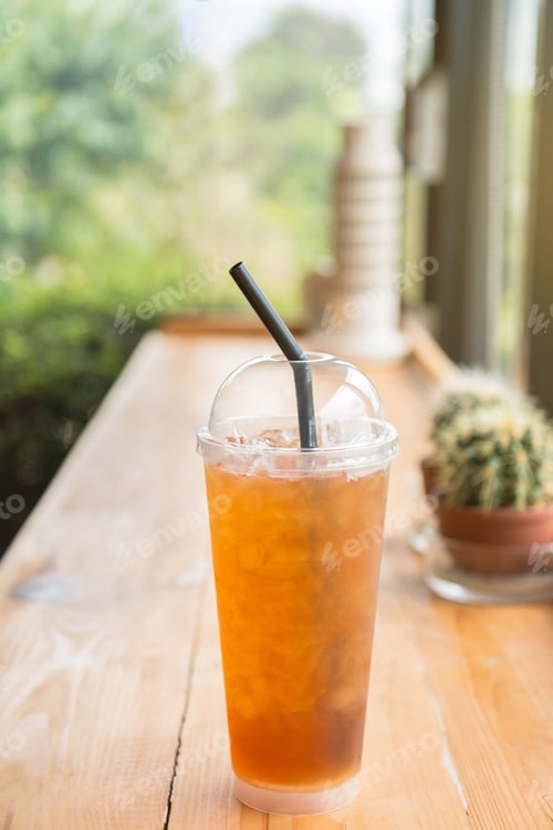 Preview: Iced lemon tea in a tall plastic cup on the wooden table. In homemade coffee shop.