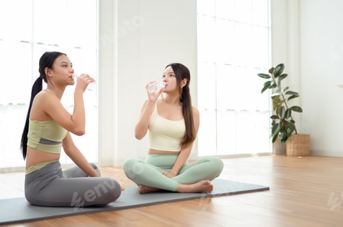 Preview: Two young Asian woman friends relaxing after doing Yoga at home.