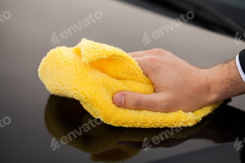 Preview: Cleaning car. Man holds the microfiber in hand and polishes the car