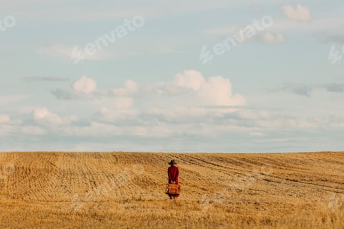 Preview: Stylish woman in vintage hat red coat with suitcase on wheat field in countryside