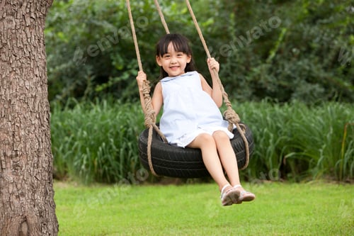 Preview: Cheerful little Chinese girl playing on a swing