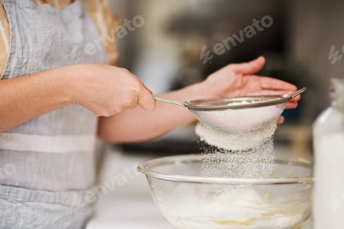 Preview: Make sure to sift your flour. Cropped shot of a woman sifting flour into a glass bowl.