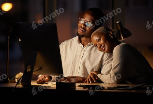 Preview: Shot of two affectionate businesspeople working together on a computer in an office at night