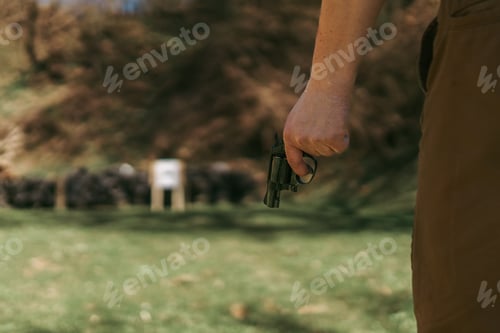 Preview: Unrecognizable man with revolver preparing to shot target on shooting range outdoors.
