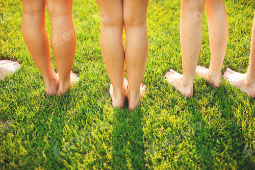 Preview: Barefoot friends standing side by side on a lush green lawn