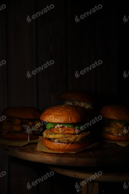 Preview: Classical burgers on wooden table with dark background