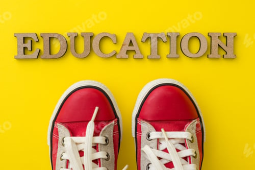 Preview: The concept of education. Word education red childrens sneakers with yellow background