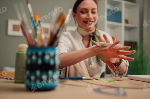 Preview: Female artist cleaning her hands after painting in her workshop