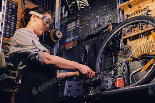 Preview: Female bicycle mechanic cutting and polish bike part.