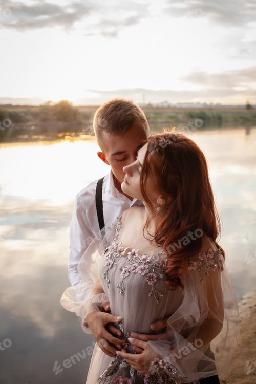Preview: Loving Couple Embracing at Sunset Near Calm Waters