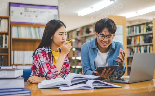 Preview: Students are consulting each other working on laptops and searching for books to study