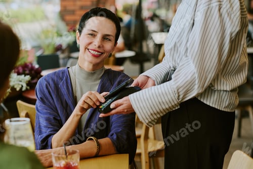 Preview: Middle Aged Woman Smiling While Paying Bill with Credit Card