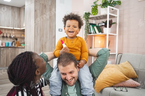 Preview: Joyful multiracial family enjoying playtime at home in the evening