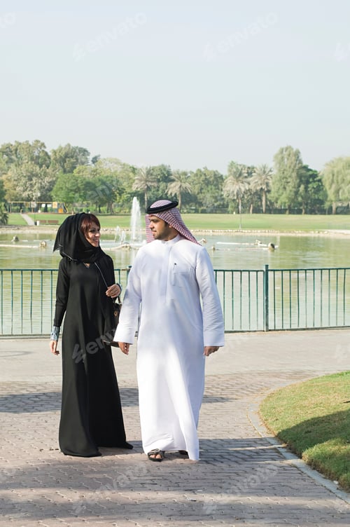 Preview: A couple in traditional Middle Eastern attire enjoys a sunny day by the lake.