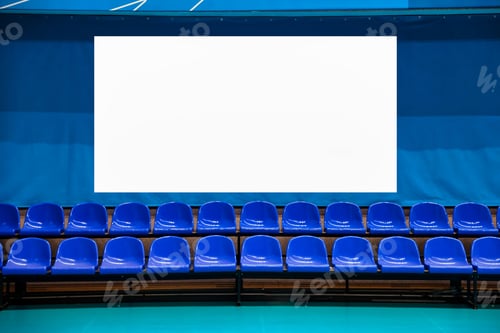 Preview: Row of Blue Seats Faces a Blank White Billboard Inside a Gymnasium