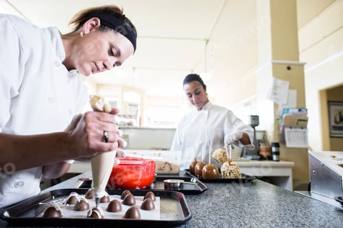 Preview: Caucasian woman and Hispanic woman working on creating candy in a candy shop.