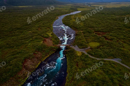 Preview: a stream runs through an open land with mountains in the background