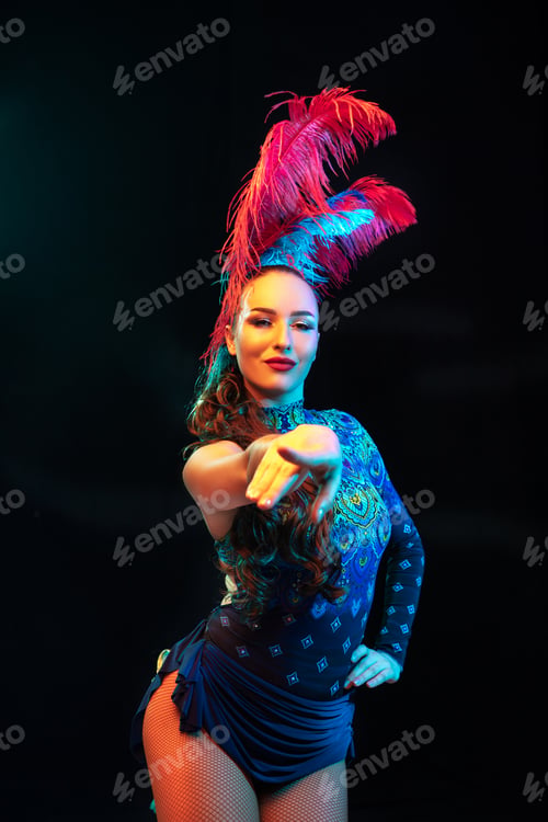 Preview: Beautiful young woman in carnival and masquerade costume in colorful neon lights on black background