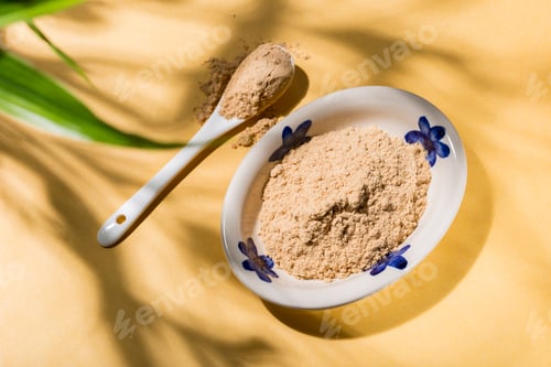 Preview: nutritious carob powder on a yellow background, top view
