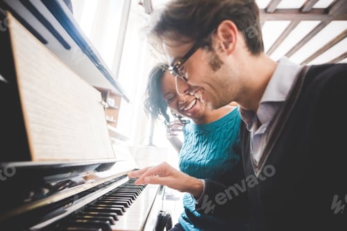Preview: Multiethnic happy couple playing piano together at home