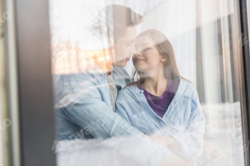 Preview: view through window on couple going to kiss with closed eyes