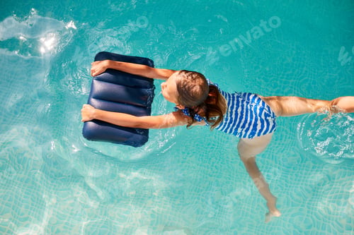 Preview: Happy little girl having fun in the swimming pool, dives and swim,