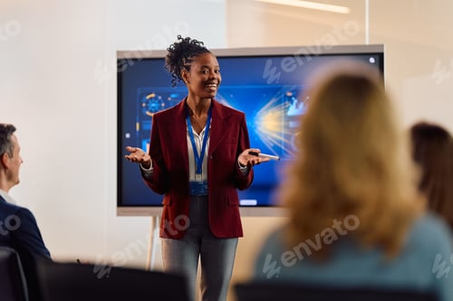 Preview: Happy black businesswoman talking to entrepreneurs during an education event in conference room.