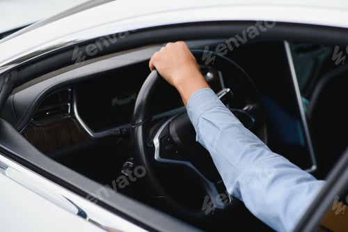 Preview: Businessman holding steering wheel while driving modern electric car on the street road