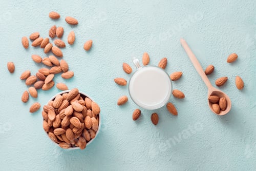 Preview: Peeled almonds in a bowl and almond milk in a glass on a light background.