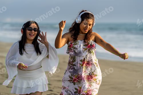 Preview: Young women enjoying music on beach at sunset