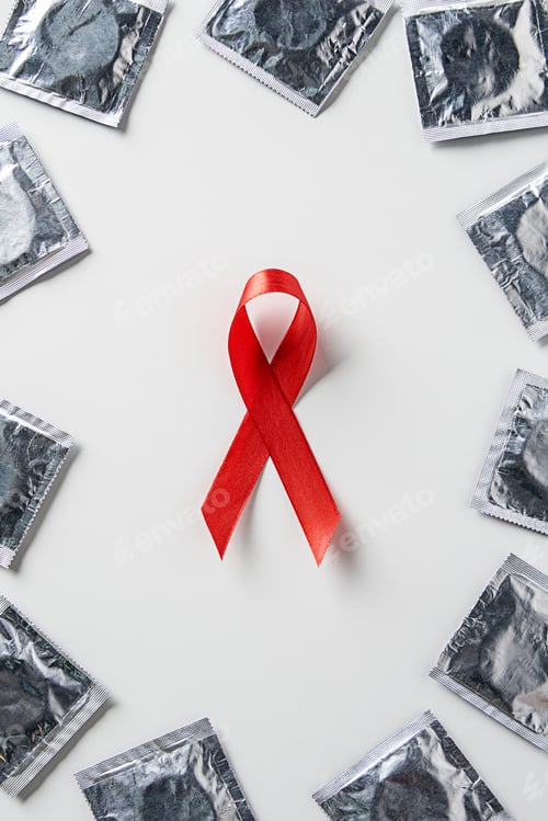 Preview: top view of aids awareness red ribbon and silver condoms on white background