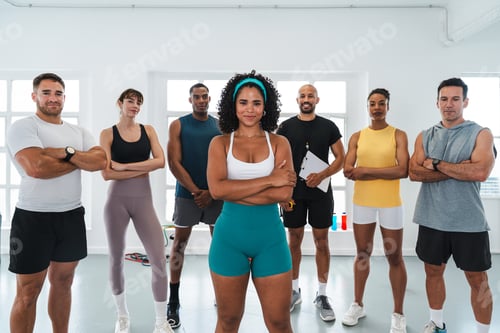 Preview: Fitness trainer posing with group in gym after functional training workout