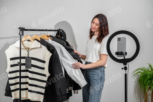 Preview: Fashion blogger recording vlog about clothes. Female blogger or stylist standing in front of camera
