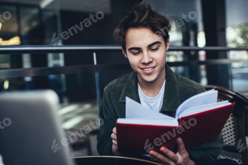 Preview: Positive male student reading notebook while studying