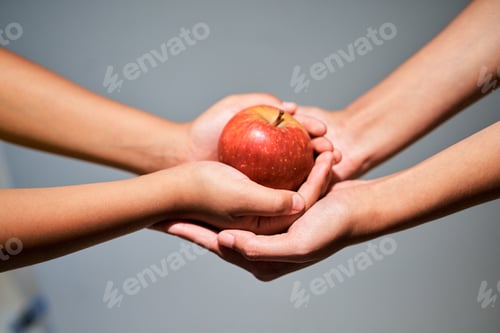 Preview: An apple a day...Studio shot of an unrecognizable woman giving a child an apple.