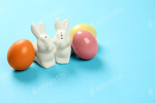 Preview: Ceramic Easter bunnies and dyed eggs on color background, space for text
