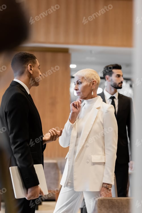 Preview: african american security man with laptop talking to thoughtful senior lady near bi-racial